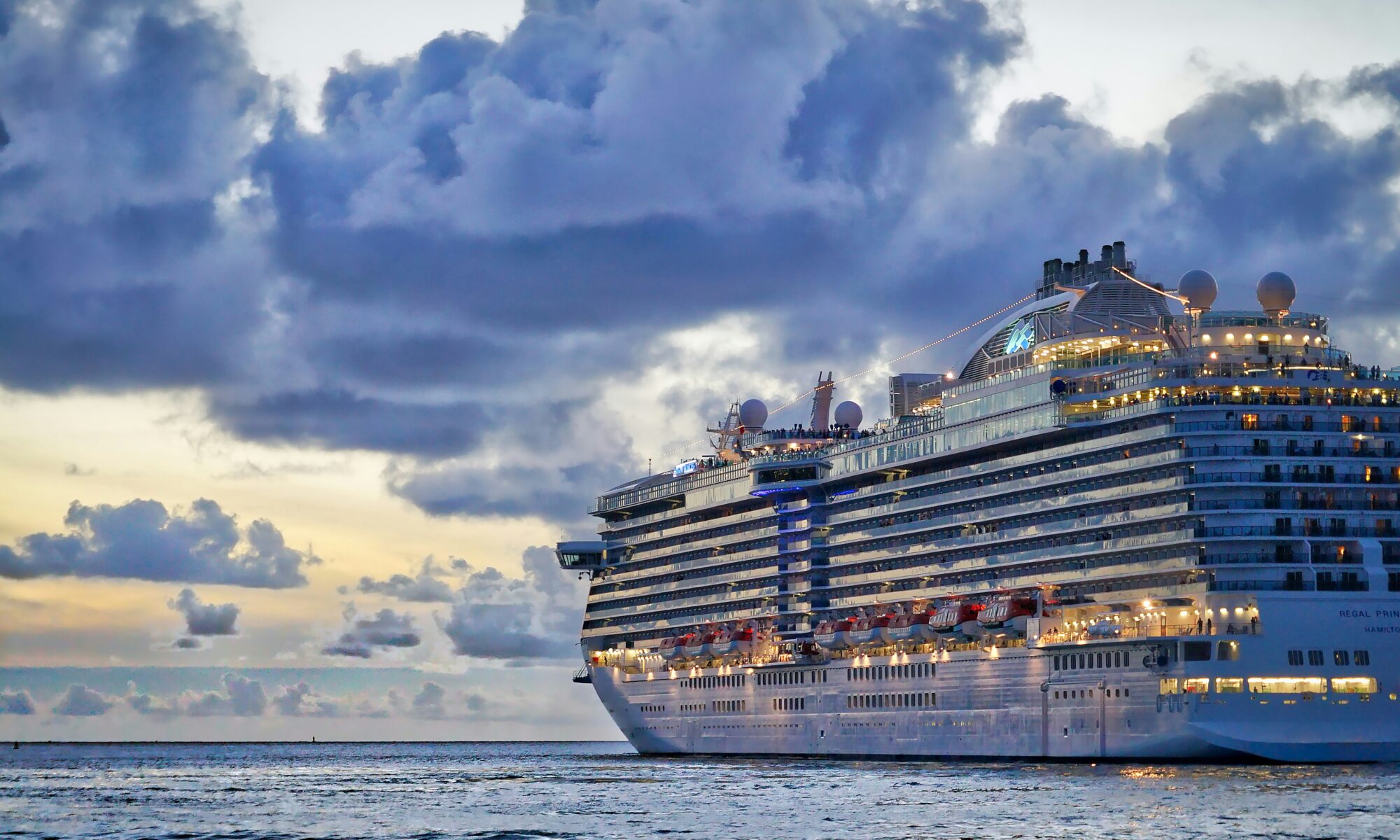 Aerial view of a large Royal Caribbean cruise ship sailing on the vibrant blue ocean at sunset