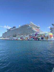 Exterior side profile of the Norwegian Aqua cruise ship docked in port, showcasing colorful hull art and upper passenger decks.