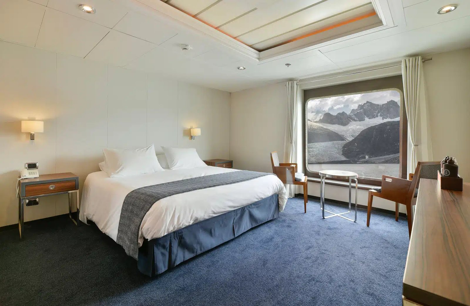 Spacious AA Superior cabin with large panoramic window and double bed on Australis Cruises