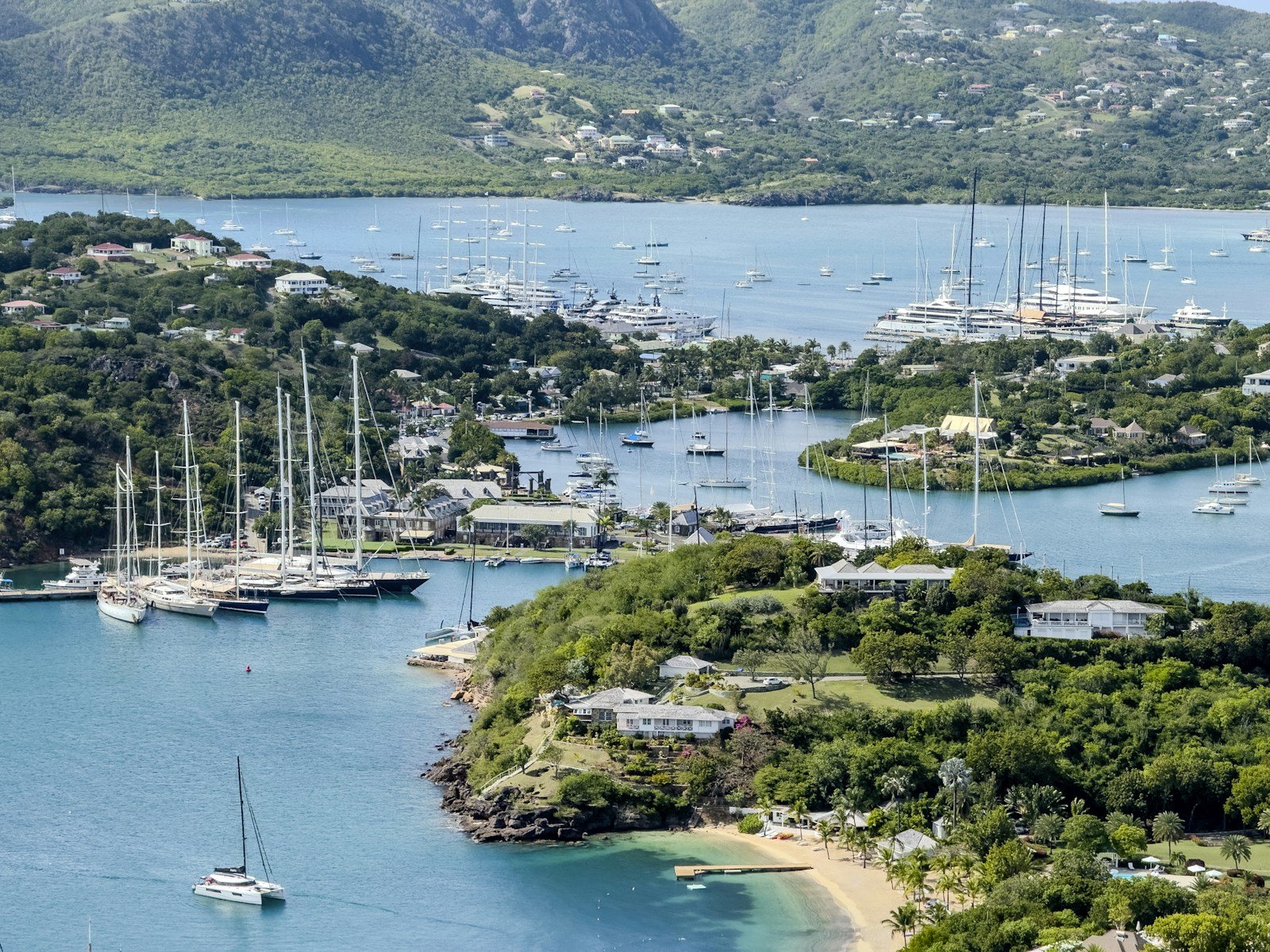 A group of luxury catamarans anchored in a secluded Caribbean tropical cove with turquoise water