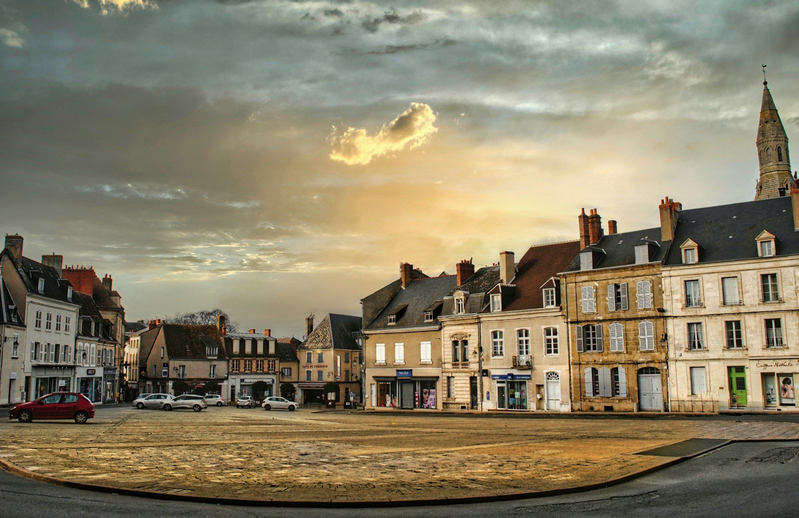 A cobblestone town square surrounded by historic European architecture during golden hour