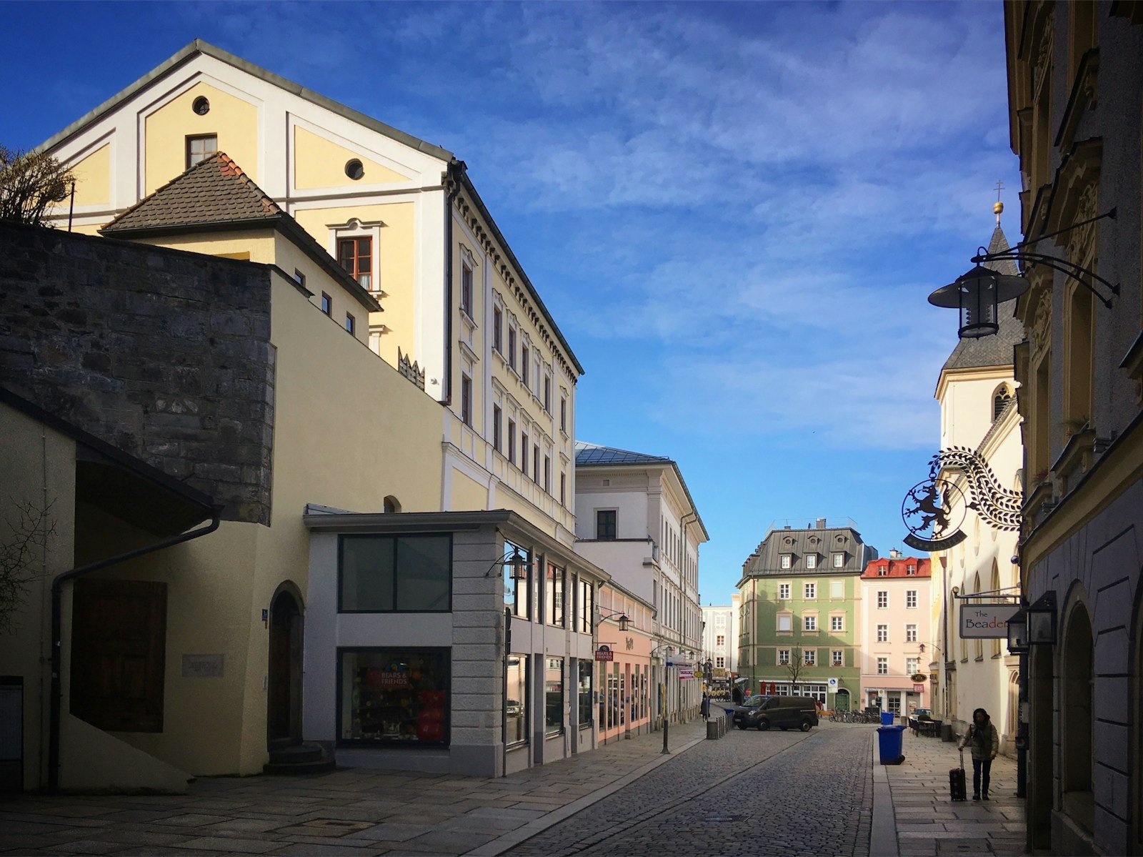 Historic European street with ornate facades under a bright blue sky during a cultural walking tour