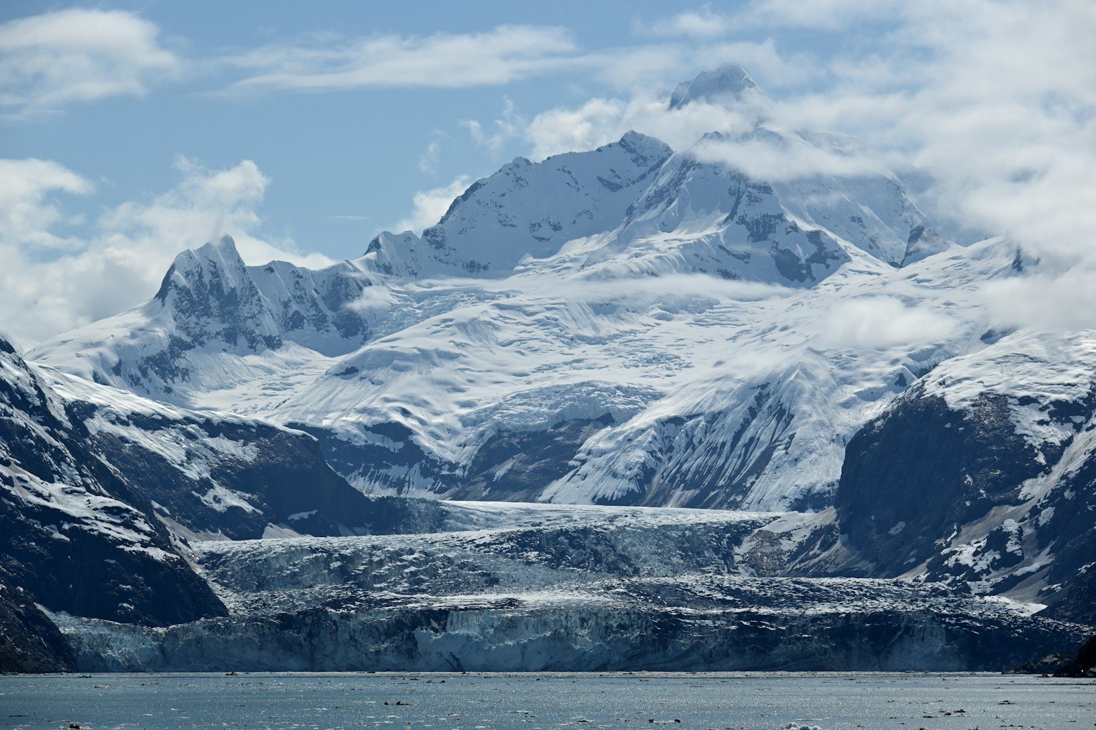 Towering snow-capped mountains and massive tidewater glacier in Glacier Bay National Park Alaska