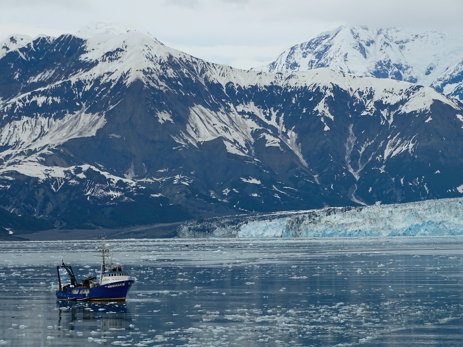 UnCruise small expedition ship sailing close to a massive tidewater glacier in Alaska