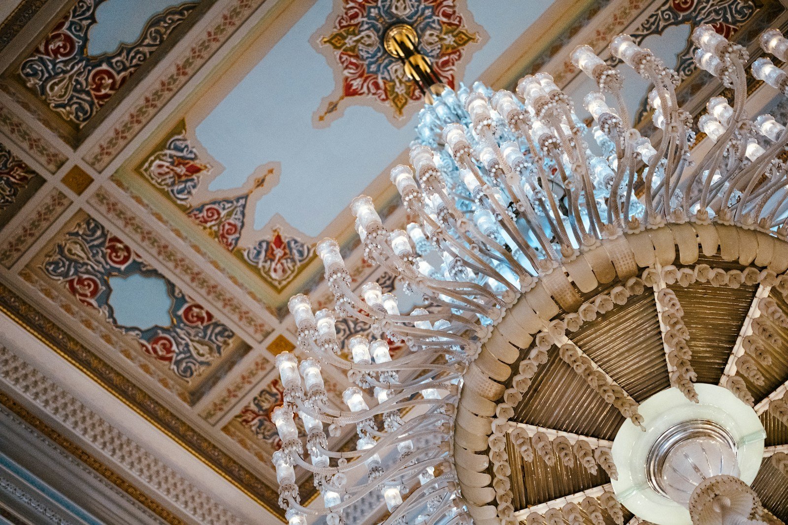 Ornate hand-painted ceiling and gilded crystal chandelier in a European palace setting