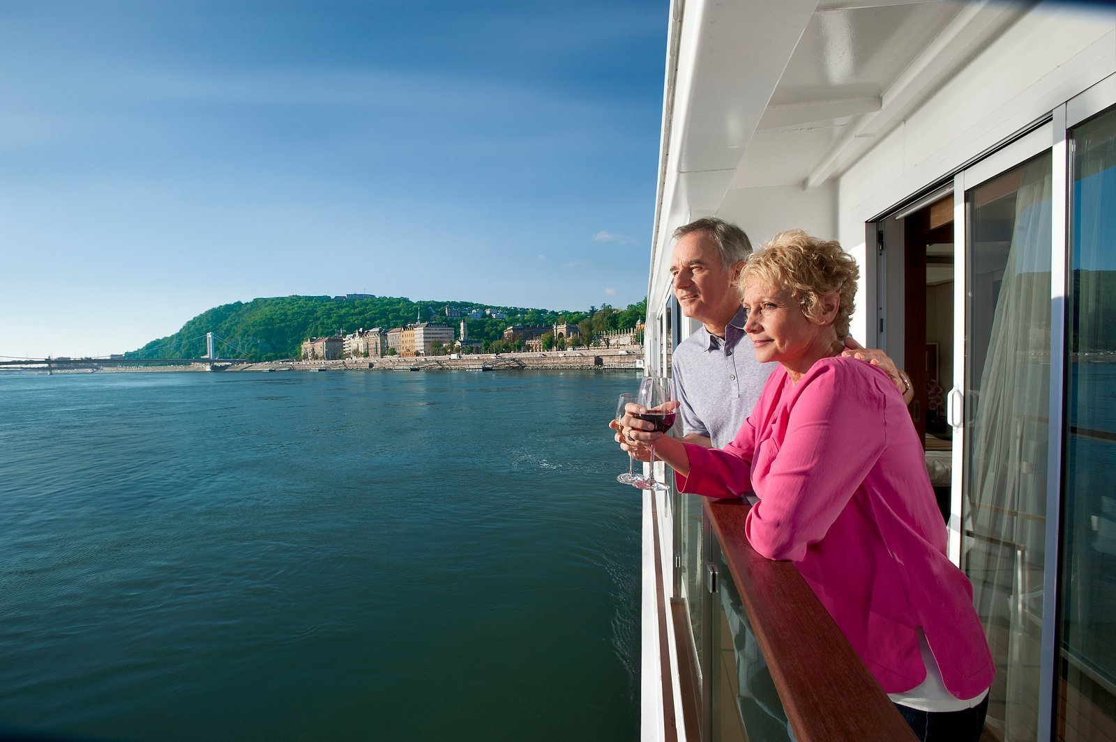 Couple sitting on private balcony chairs of a Viking Longship Veranda stateroom enjoying river cruise views