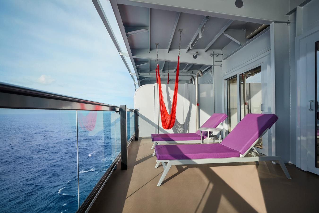 Official Virgin Voyages Gorgeous Suite private terrace with handwoven red hammock and purple loungers