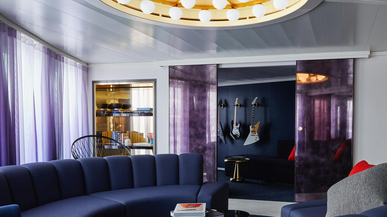 Official Virgin Voyages Massive Suite living room with curved sofa and music room with wall-mounted guitars