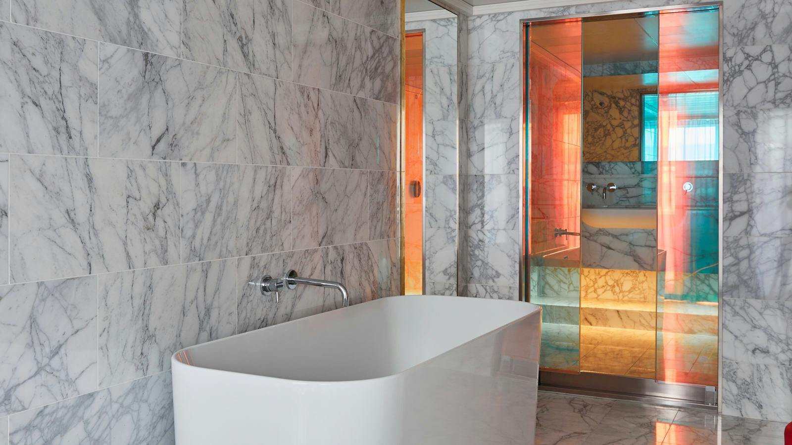 Official Virgin Voyages Massive Suite marble bathroom with freestanding soaking tub and peek-a-boo rain shower