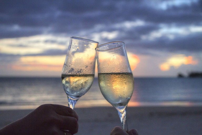 Affluent couple toasting with champagne at sunset on a luxury vacation booked through a referral travel advisor